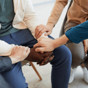 Hands clasped together in supportive gesture during a Widow and Widower Support Group meeting.